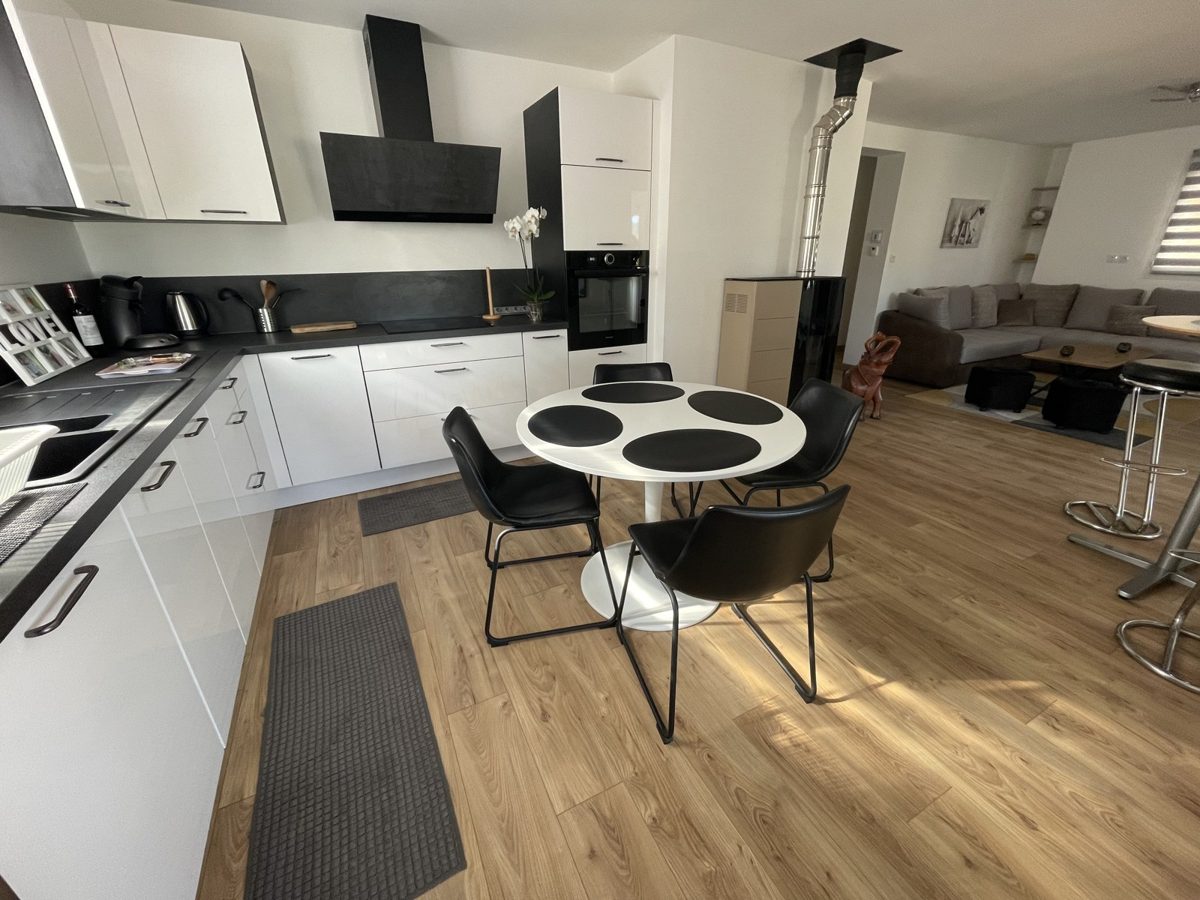 Cuisine ouverte sur séjour, parquet clair, photographiée au grand angle